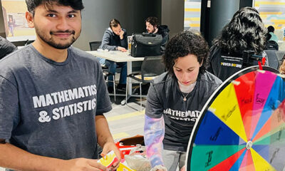 A student in a "Mathematics & Statistics" stands next to a prize wheel.