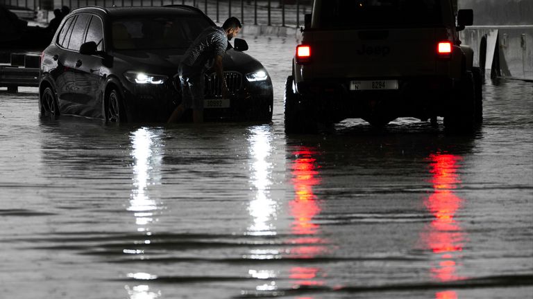 A man tries to work on his stalled SUV in standing water in Dubai.
Pic: AP