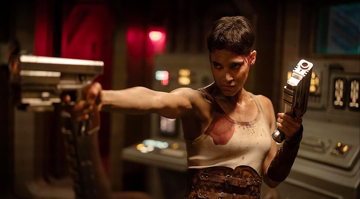 A tough woman in a tank top prepares to fire two space pistols