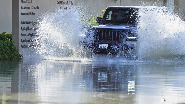 An SUV drives through floodwater covering a road in Dubai.
Pic: Reuters