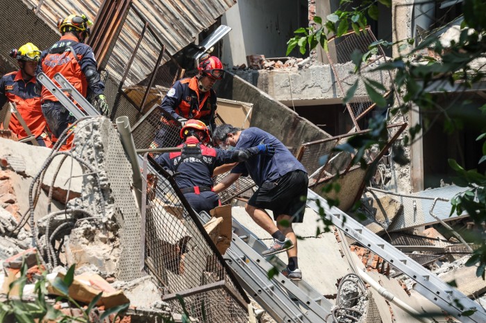 Emergency workers assist a survivor from a damaged building in New Taipei City