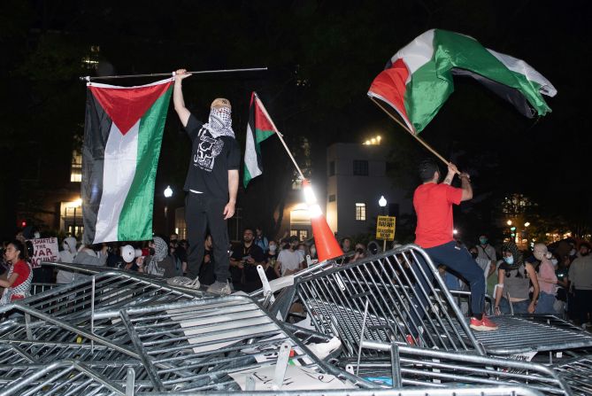 Students from George Washington University stand on top of police barricades as they protest in Washington, DC, on April 29.