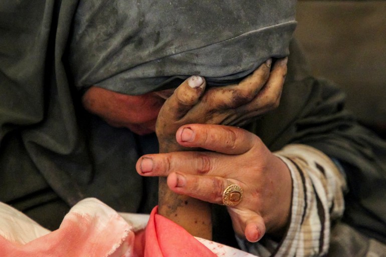 Palestinian woman Buthayna Abu Jazar reacts as she holds the hand of her son Hazma, who was killed in an Israeli strike, amid the ongoing conflict between Israel and Hamas, in Rafah, in the southern Gaza Strip May 9, 2024. REUTERS/Hatem Khaled TPX IMAGES OF THE DAY