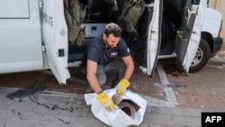 A member of the bomb squad of the Israeli police collects debris after a rocket fired by Palestinian militants struck in the Israeli city of Herzliya on May 26, 2024.