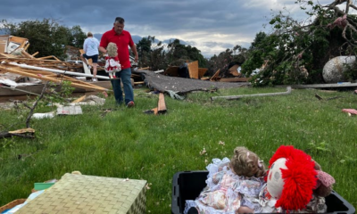 A man helps gather June Handsacker's porcelain dolls from the wreckage of her home.