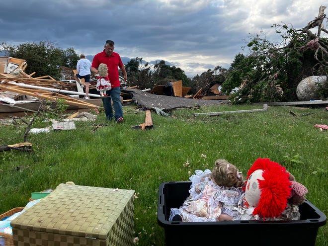 A man helps gather June Handsacker's porcelain dolls from the wreckage of her home.