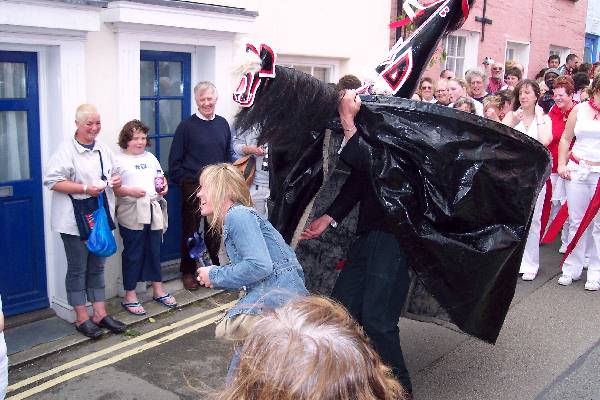 The red 'obby 'oss captures a passing maiden during the Padstow May Day festival. Photo credit: S.G. Bailey on Wikimedia Commons.