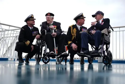 Jordan Pettitt/PA Media Royal Navy Commander Glen Hinson, D-Day veteran Jim Grant, Royal Navy Commodore John Boyce, and D-Day veteran Charles Horne, on board the Brittany Ferries ship Mont St Michel