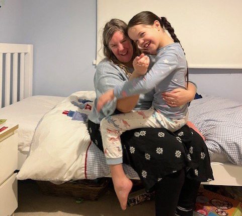 Kate on her daughter's bed, with her daughter on her lap