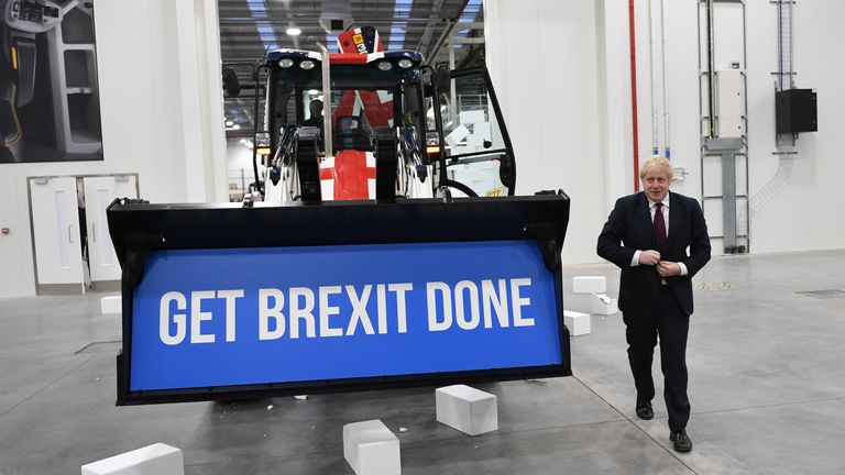 Boris Johnson walks away after driving a Union flag-themed JCB through a fake wall emblazoned with the word 