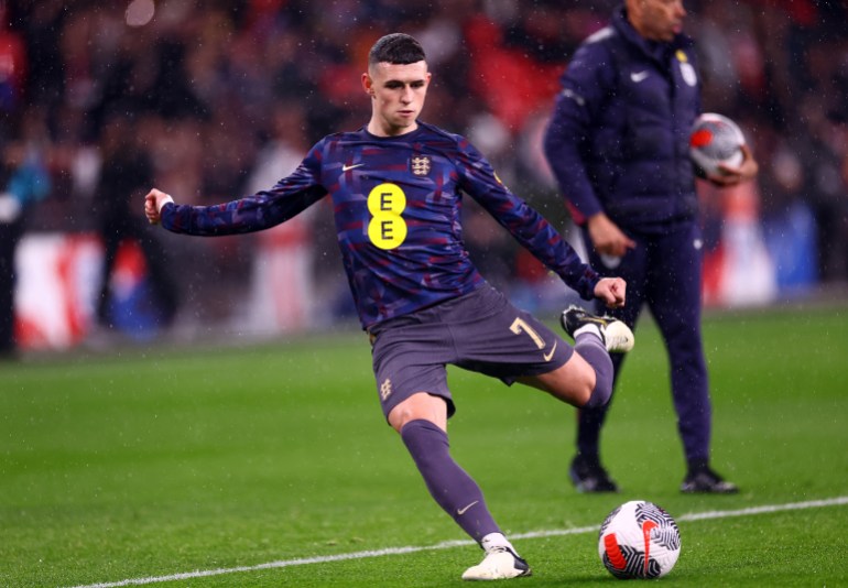 Football player strikes ball during warmup.