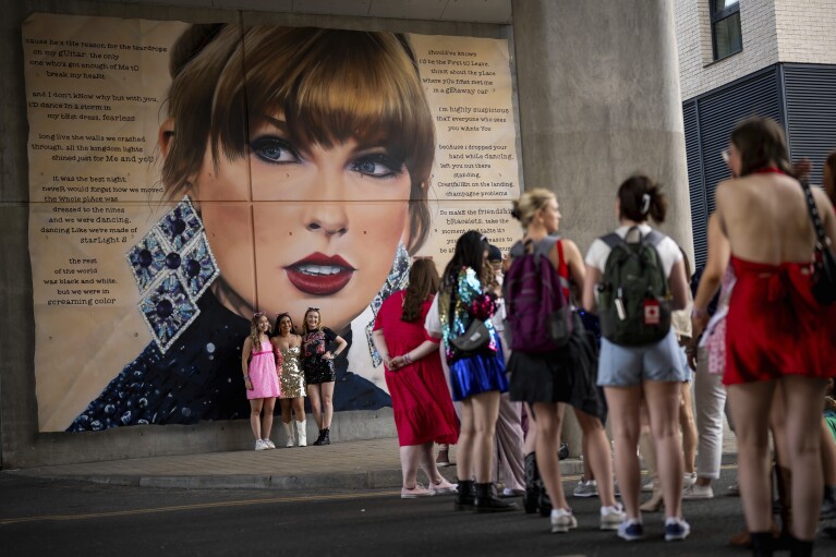 Taylor Swift fans pose for a photograph besides a mural, commissioned by London Mayor Sadiq Khan, before the first London concert of the Eras Tour on Friday, June 21, 2024 in London. (Photo by Scott A Garfitt/Invision/AP)