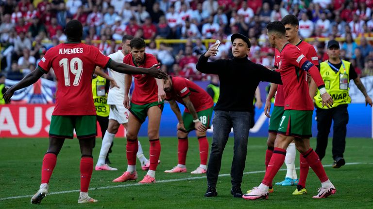 A pitch invader tries to take a selfie with Portugal's Cristiano Ronaldo during a Group F match between Turkey and Portugal at the Euro 2024 soccer tournament in Dortmund, Germany, Saturday, June 22, 2024. (AP Photo/Themba Hadebe)