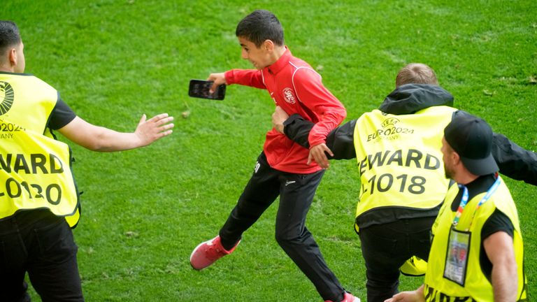 Stewards catch a young pitch invader who ran to Portugal's Cristiano Ronaldo during a Group F match between Turkey and Portugal at the Euro 2024 soccer tournament in Dortmund, Germany, Saturday, June 22, 2024. (AP Photo/Michael Probst)