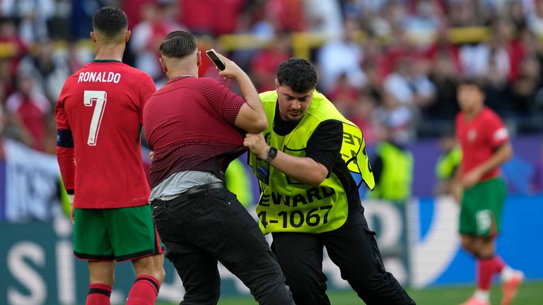 Steward catches a pitch invader that ran to Portugal's Cristiano Ronaldo during a Group F match between Turkey and Portugal at the Euro 2024 soccer tournament in Dortmund, Germany, Saturday, June 22, 2024. (AP Photo/Darko Vojinovic)