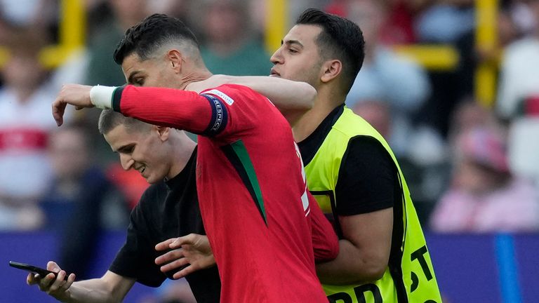 A pitch invader tries to take a selfie with Portugal's Cristiano Ronaldo as a steward moves him out during a Group F match between Turkey and Portugal at the Euro 2024 soccer tournament in Dortmund, Germany, Saturday, June 22, 2024. (AP Photo/Themba Hadebe)