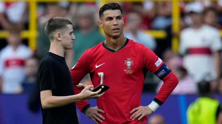 A pitch invader stands next to Portugal's Cristiano Ronaldo during a Group F match between Turkey and Portugal at the Euro 2024 soccer tournament in Dortmund, Germany, Saturday, June 22, 2024. (AP Photo/Themba Hadebe)