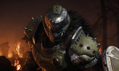 The DOOM Slayer stares down the viewer, lit by flames in the background.