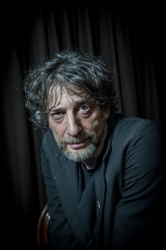 Neil Gaiman wearing a suit and looking at the camers