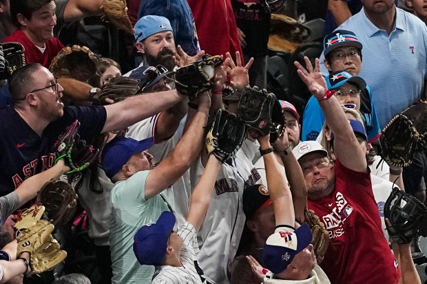 Fans reach to catch a home run ball hit by...