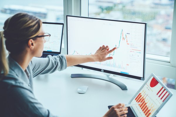 A person pointing to a stock chart on a computer screen.