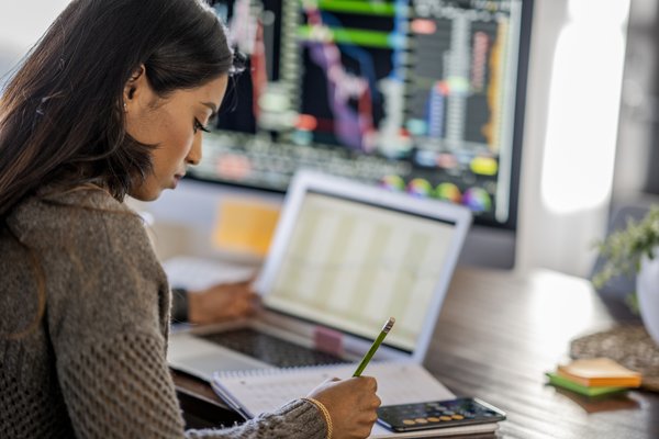 Person reviewing data on multiple computer monitors.