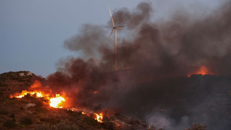 A wildfire burns next to a wind turbine near the village of Petries on the island of Evia.
Pic: Reuters