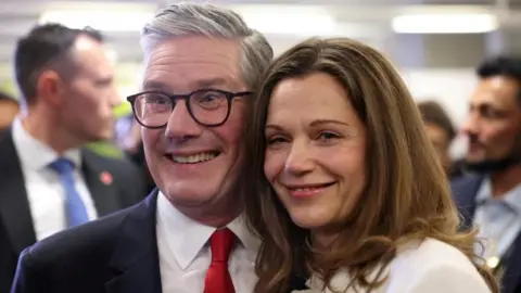 Reuters Sir Keir Starmer and Lady Starmer stand beside each other smiling