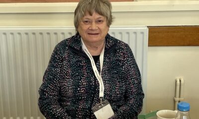 A woman wearing a lanyard sat behind a desk at a polling station