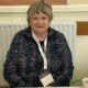 A woman wearing a lanyard sat behind a desk at a polling station