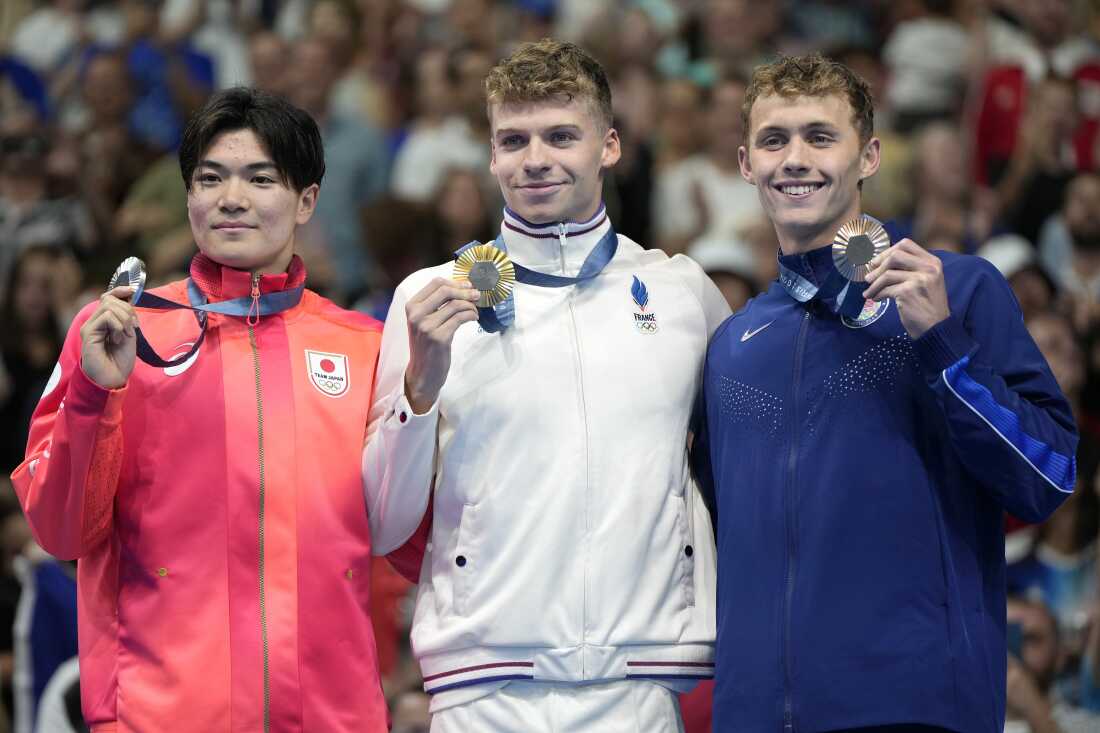 Gold medalist Leon Marchand, center, of France, stands with silver medalist Tomoyuki Matsushita, left, of Japan, and bronze medalist Carson Foster, of the United States, following the men's 400-meter individual medley final at the 2024 Summer Olympics, Sunday, July 28, 2024, in Nanterre, France. (AP Photo/Matthias Schrader)