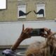 A woman stops to photograph a new artwork depicting two elephants poking their heads out of blocked out windows unveiled by Banksy on the side of a building at the junction of Edith Grove and Edith Terrace, in Chelsea, south west London. Picture date: Tuesday August 6, 2024.