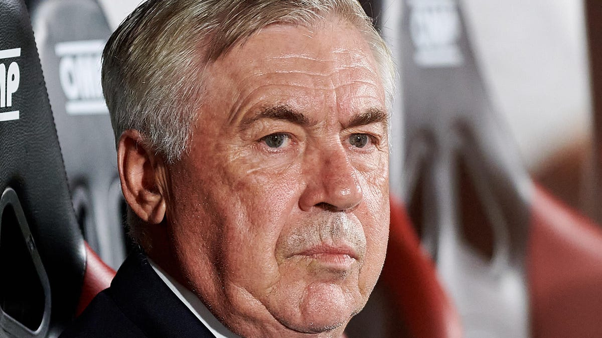 Close up image of Carlo Ancelotti, head coach of Real Madrid sitting in a dugout, looking to his right.