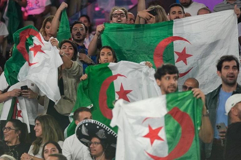 Algeria fans cheer as Algeria's Imane Khelif prepares to fight China's Yang Liu in their women's 66 kg final boxing match at the 2024 Summer Olympics, Friday, Aug. 9, 2024, in Paris, France. (AP Photo/Ariana Cubillos)