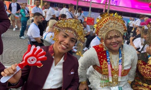 Two athletes dressed in traditional clothing pose for a photograph