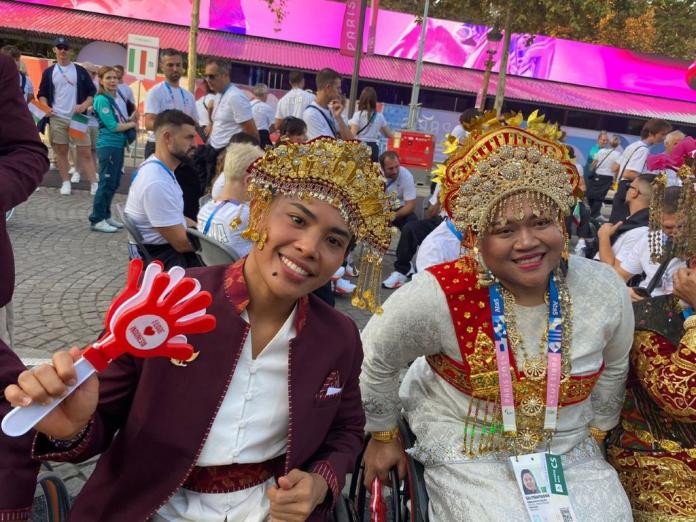 Two athletes dressed in traditional clothing pose for a photograph