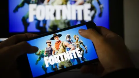 Getty Images Hands holding a mobile phone with the Fortnite logo on it