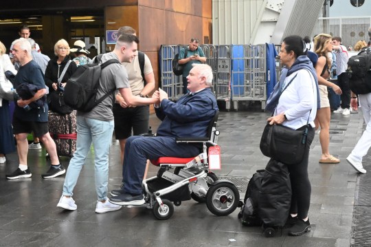 Fans approaching Eamonn Holmes in a wheelchair outside Barcelona Airport