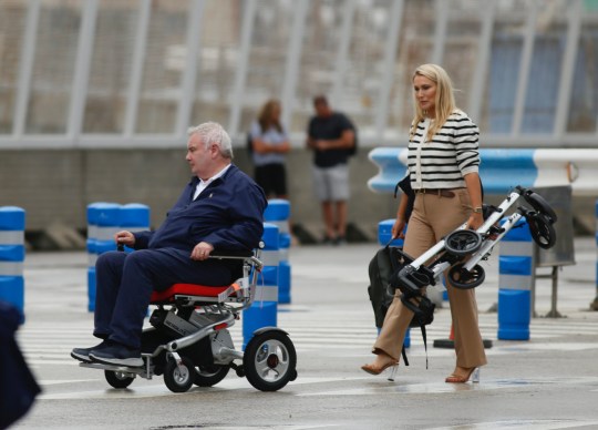 Eamonn Holmes using a wheelchair followed by Katie Alexander holding his walker