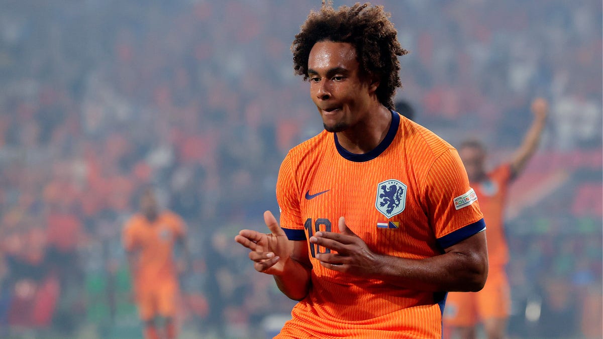 Netherlands forward Joshua Zirkzee celebrating, making gun-shaped gestures with both hands.