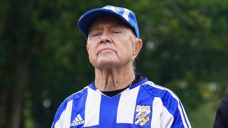 A mourner wears a IFK Goteborg football kit as he watches the funeral on a big screen outside the church. Pic: PA