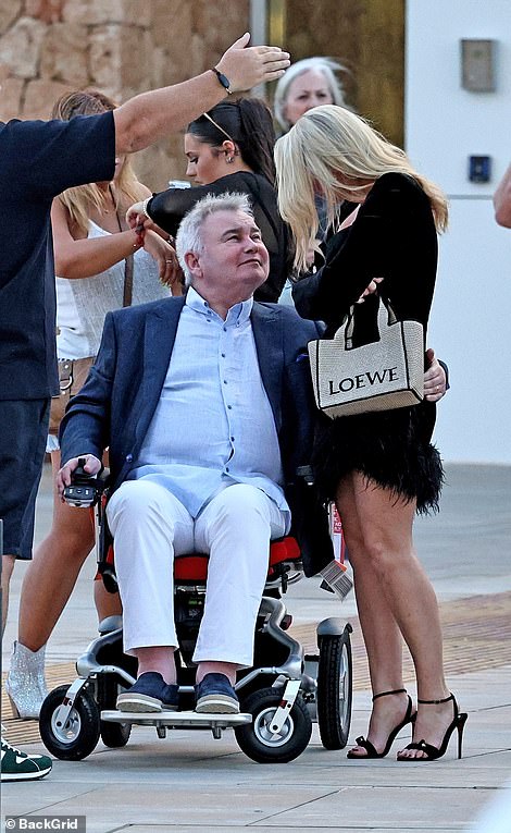 Eamonn, who was in a self-drive electric wheelchair amid his crippling back problems, looked particularly enamored with the blonde beauty as he playfully grazed her behind