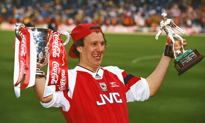 Young Paul Merson holding up Arsenal trophy