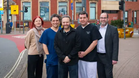 Conversation PR A group of people including local councillor Tony Dyer stand on the corner of Cannon Street and East Street in Bedminster to announce the opening of a new dentists. They are smiling at the camera.