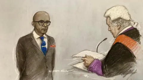 PA Media Court artist drawing of Jay Blades in a suit and tie, standing with hands behind his back, in front of Recorder of Worcester, Judge James Burbidge KC, who is wearing judge's robes and a wig, at Worcester Crown Court.