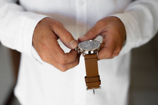 Man setting time on a watch with a brown strap