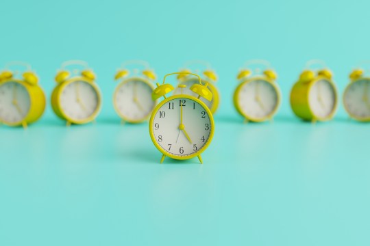 Yellow alarm clocks lined-up against a bright turquoise background