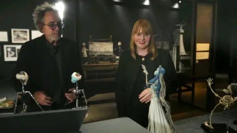 Tim Burton and BBC reporter Charlotte Gallagher looking at a display on Corpse Bride