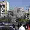 People watch a building collapse after being hit by an Israeli airstrike in Ghobeiri, Beirut, Lebanon, on Tuesday.