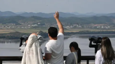 Getty Images Visitors use binoculars to look at the North Korean side of the Demilitarised Zone (DMZ) dividing the two Koreas, from South Korea's Odusan Unification Observatory in Paju on October 9, 2024. 